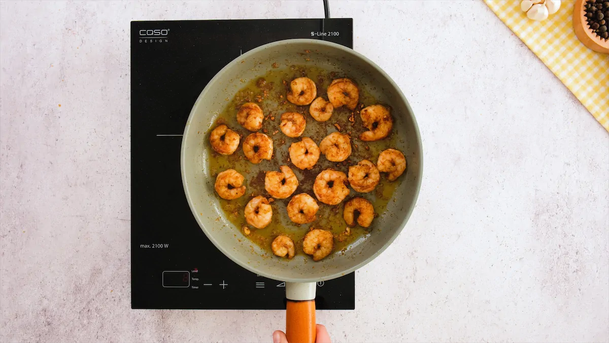 Taking a pan of cooked shrimp off the induction top.