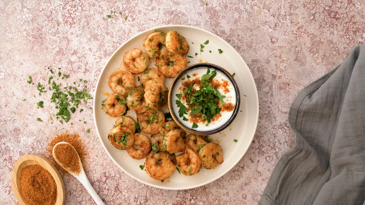 Ready-to-enjoy homemade keto Cajun shrimp on a white plate with dip.