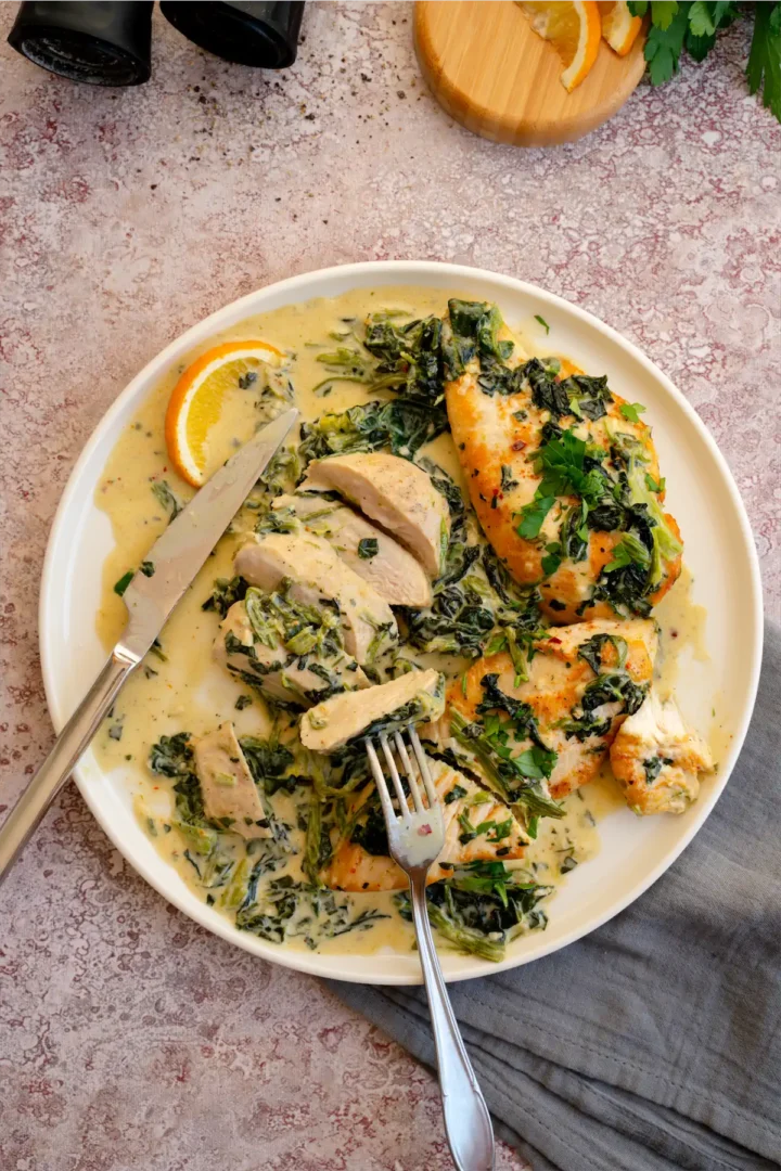 Homemade chicken Florentine on a plate with a filet cut using a knife and fork.