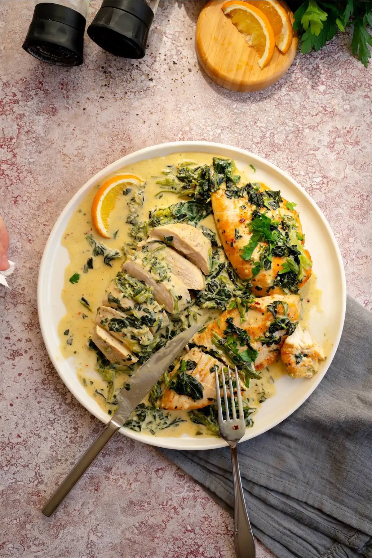 A plate featuring chicken Florentine with some filets sliced by knife and fork.