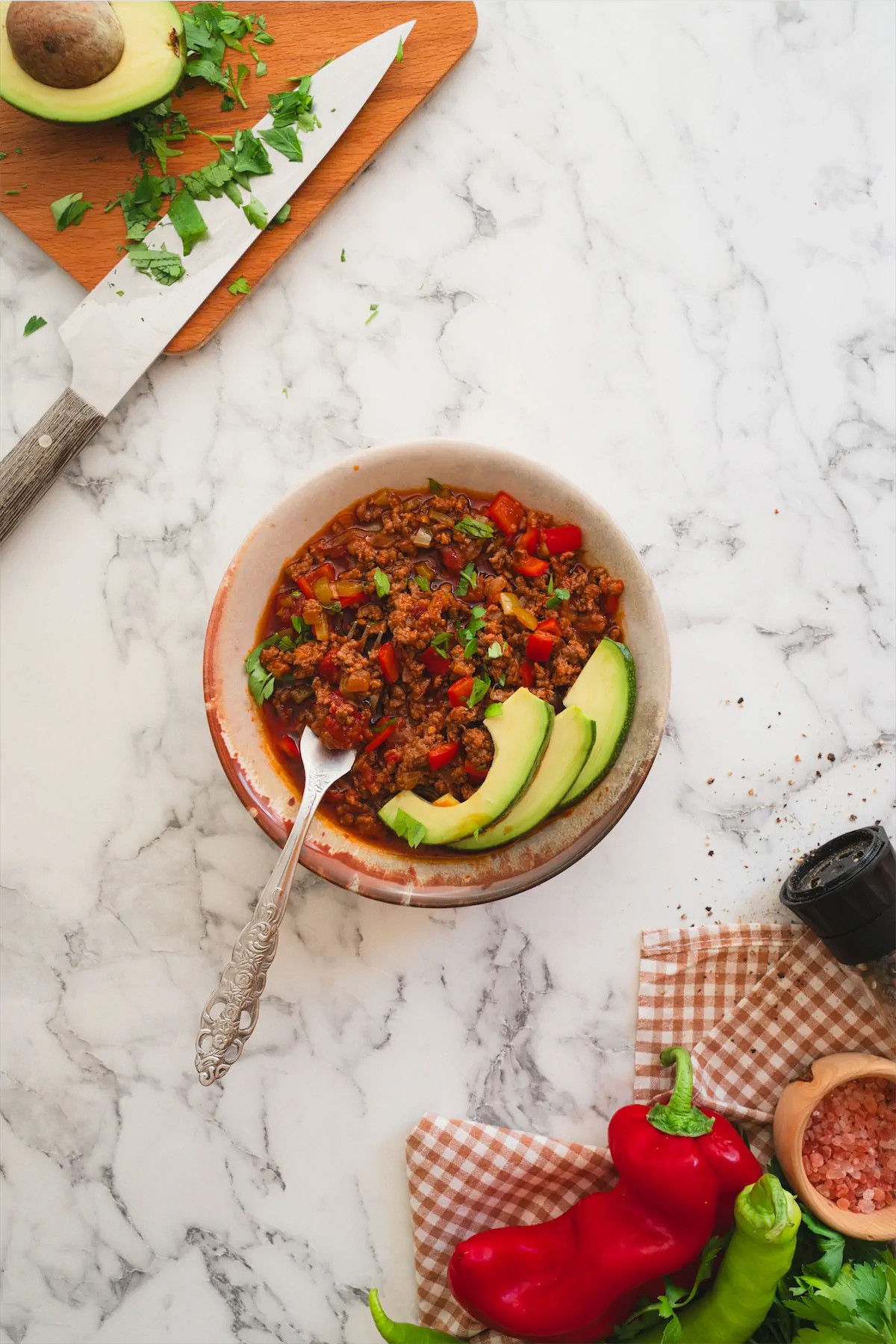 Keto chili con carne served with avocado slices in a bowl with a spoon.