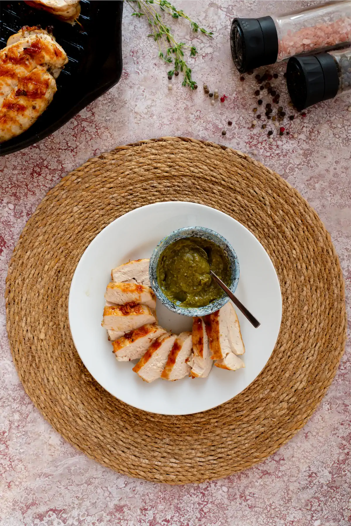 Homemade keto grilled chicken slices with a bowl of pesto sauce.