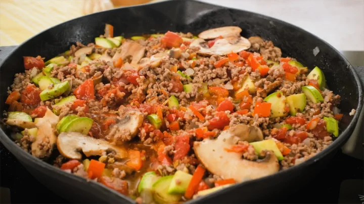 Cooking ground beef with vegetables and spices in a cast iron skillet.