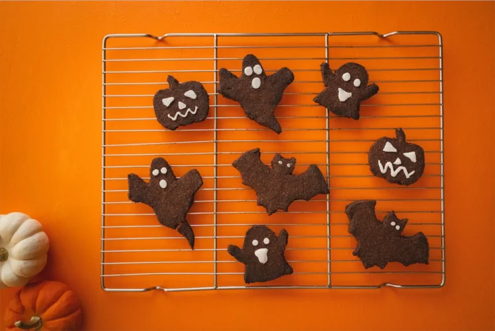 Homemade Halloween themed cookies on a wire rack on an orange table.