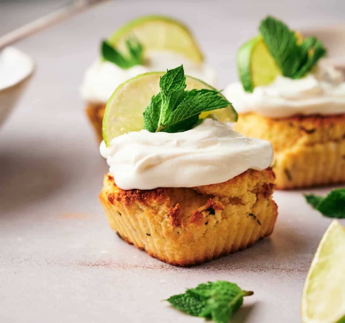 Homemade mojito-themed cupcakes, garnished with cream cheese frosting, a lemon wedge, and mint leaves.