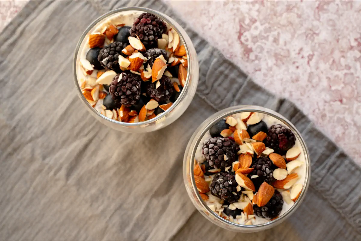 Low-carb overnight oats topped with nuts and berries in glass jars.