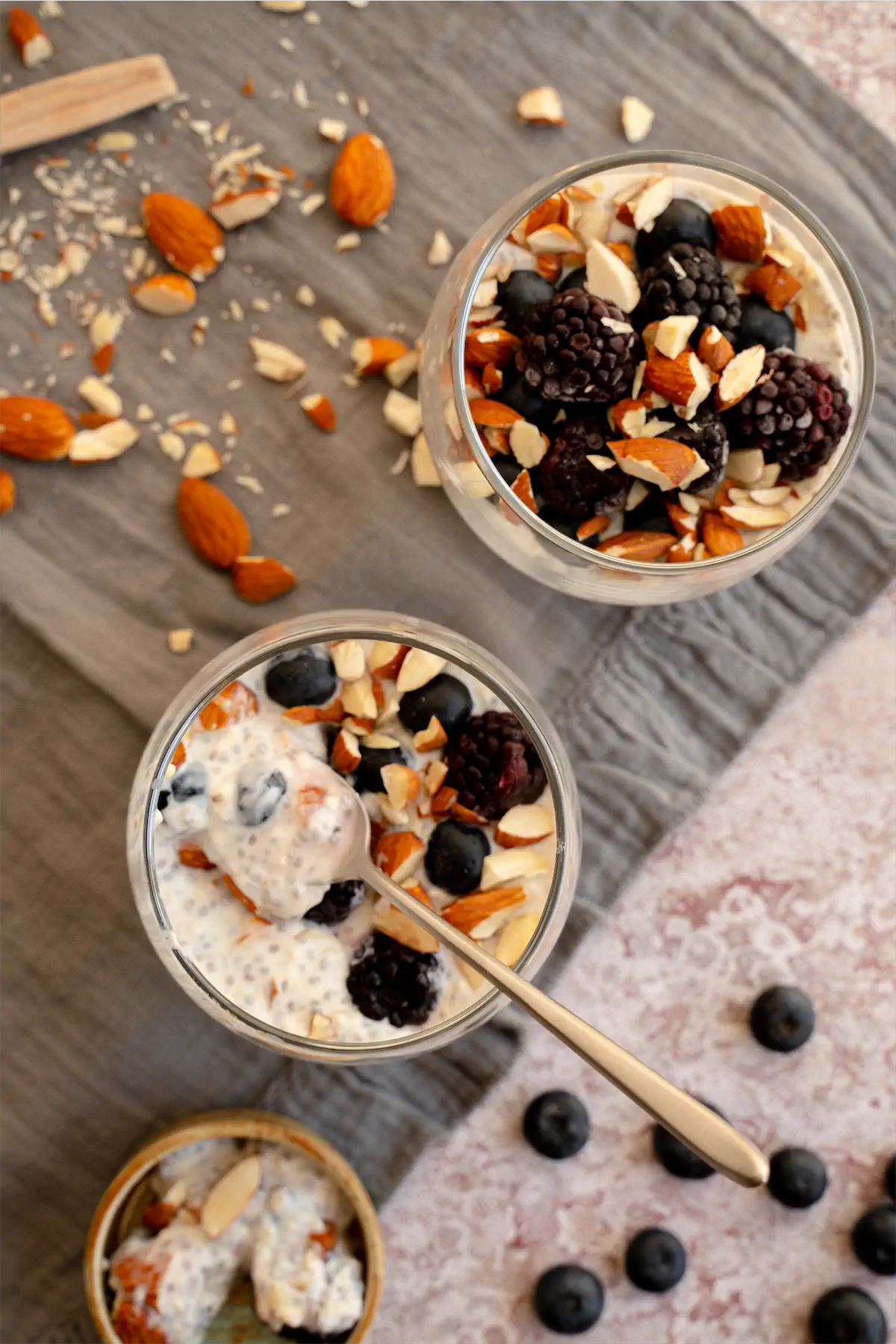 Homemade overnight oats topped with nuts and fresh berries, served in glass jars, with a spoonful ready to be eaten.