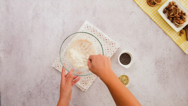 Whisking the almond milk, yogurt, vanilla extract, keto-friendly sweetener, and a pinch of salt in a mixing bowl.