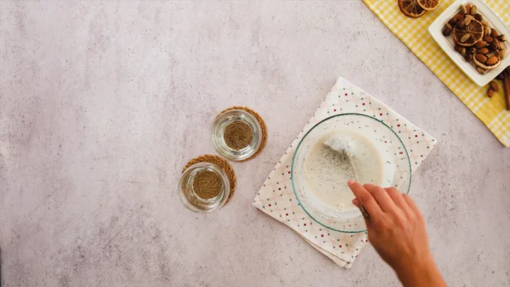 The mixture for the overnight oats is about to be transferred to the glass jars using a ladle.