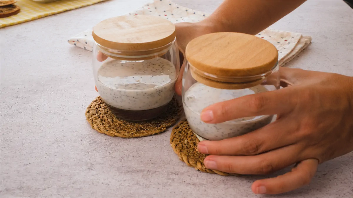 Two hands are holding lidded glass jars with the overnight oats mixture.