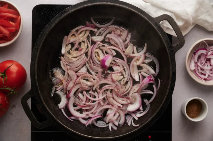 Cooking the thinly sliced onions in a cast iron skillet.