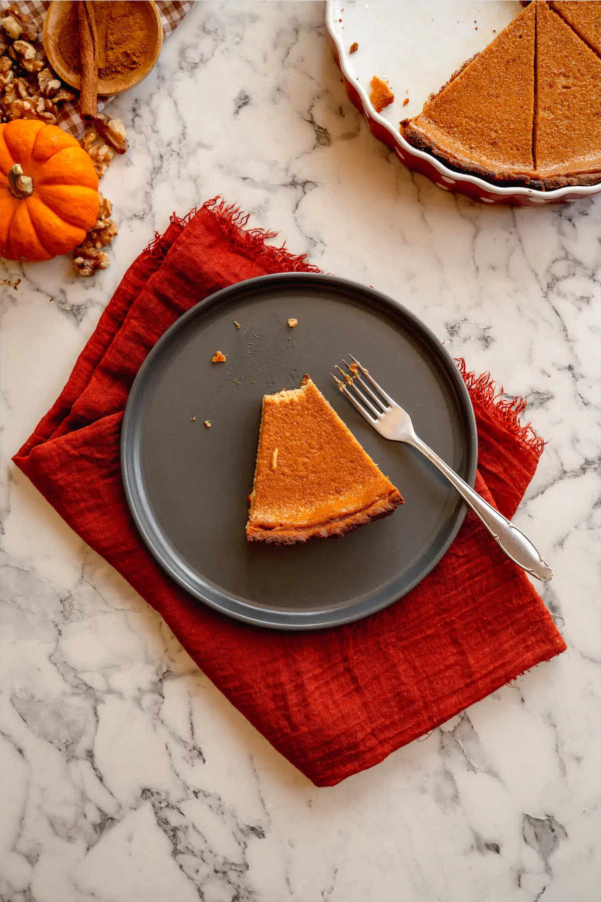 A slice of keto pumpkin pie on a plate, with a missing morsel from the pie