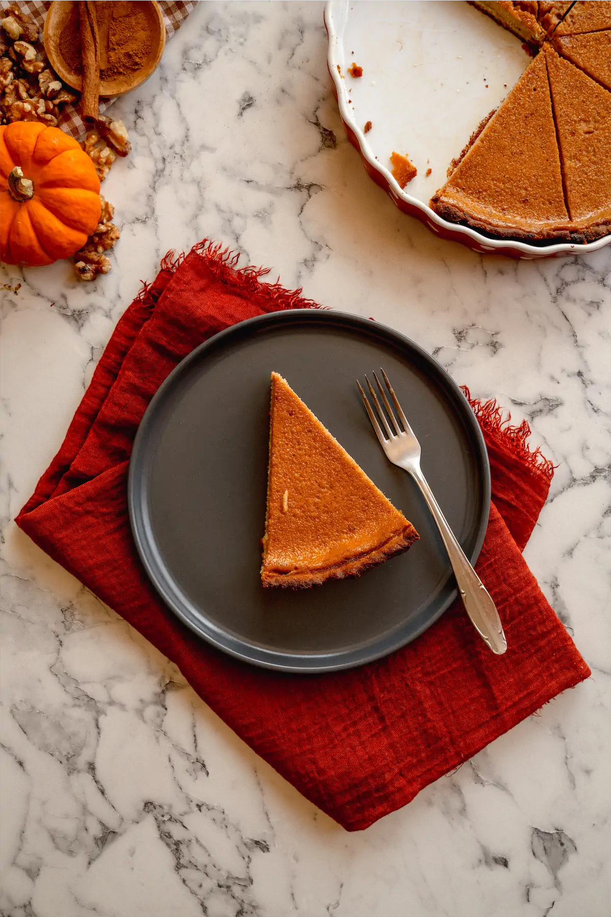 A slice of homemade pumpkin pie served on a plate with a fork.