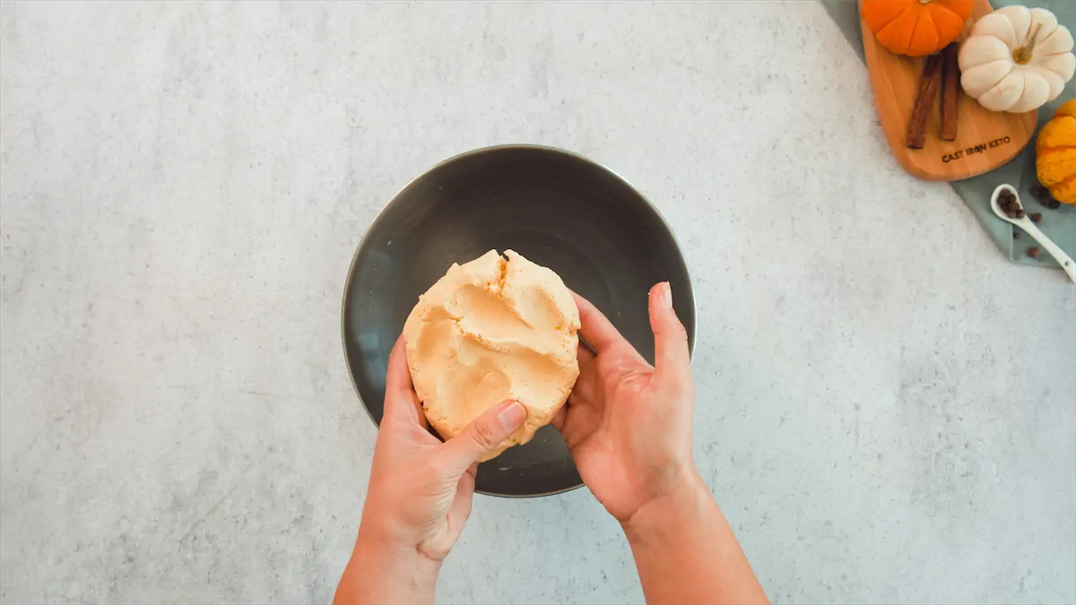 Two hands holding the dough for pumpkin pie curst.