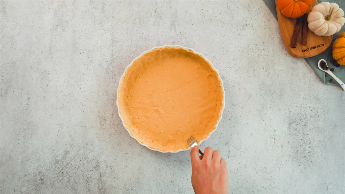 Poking holes in the homemade pumpkin pie crust using a fork.