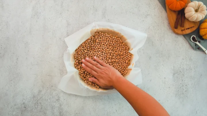Putting dried beans in the pie dish with dough to stop it from rising.
