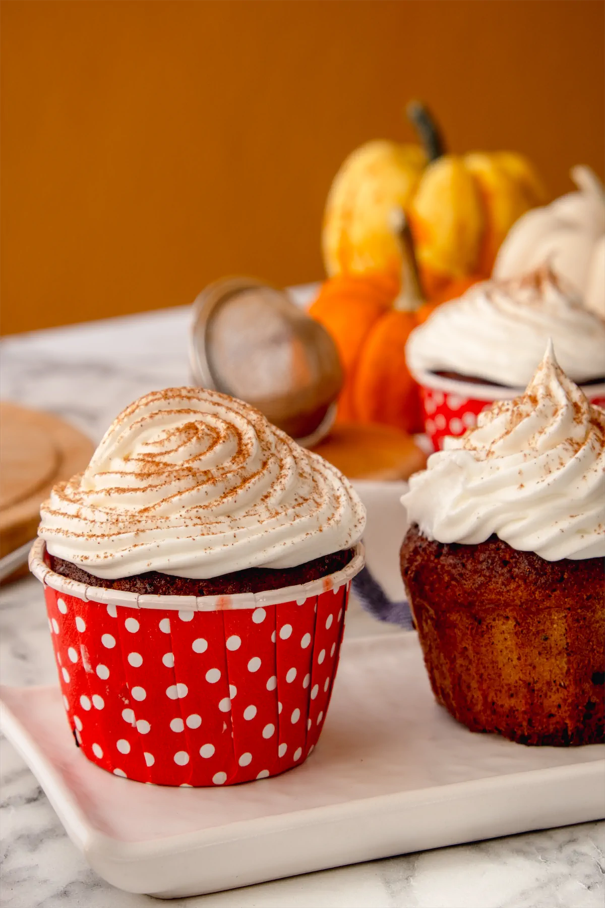 Homemade pumpkin spice cupcakes topped with whipped cream and a sprinkle of pumpkin spice.