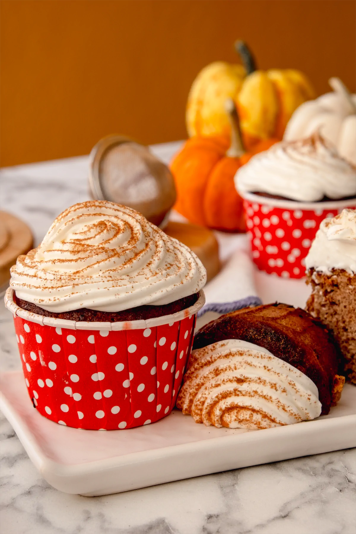 Homemade pumpkin spice latte cupcakes topped with whipped cream and a sprinkle of pumpkin spice.