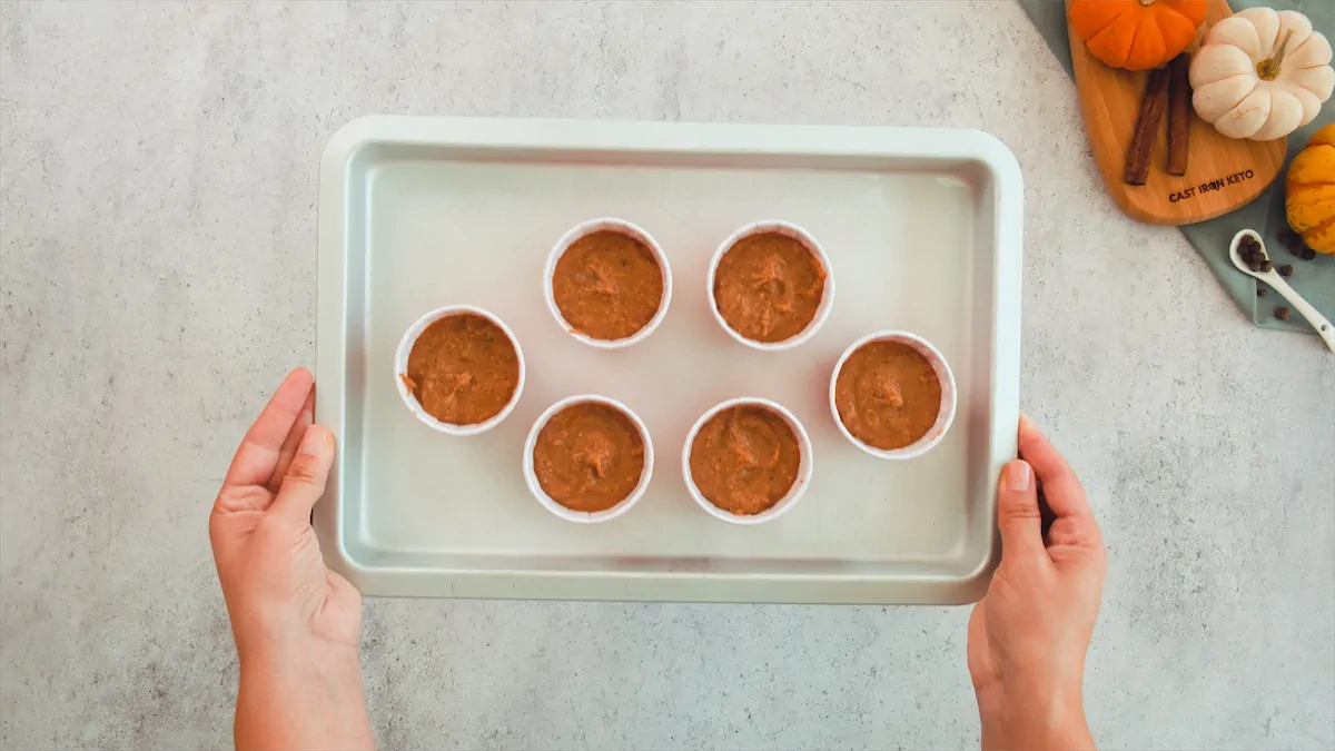 Two hands holding cupcake molds with batter held in a tray.