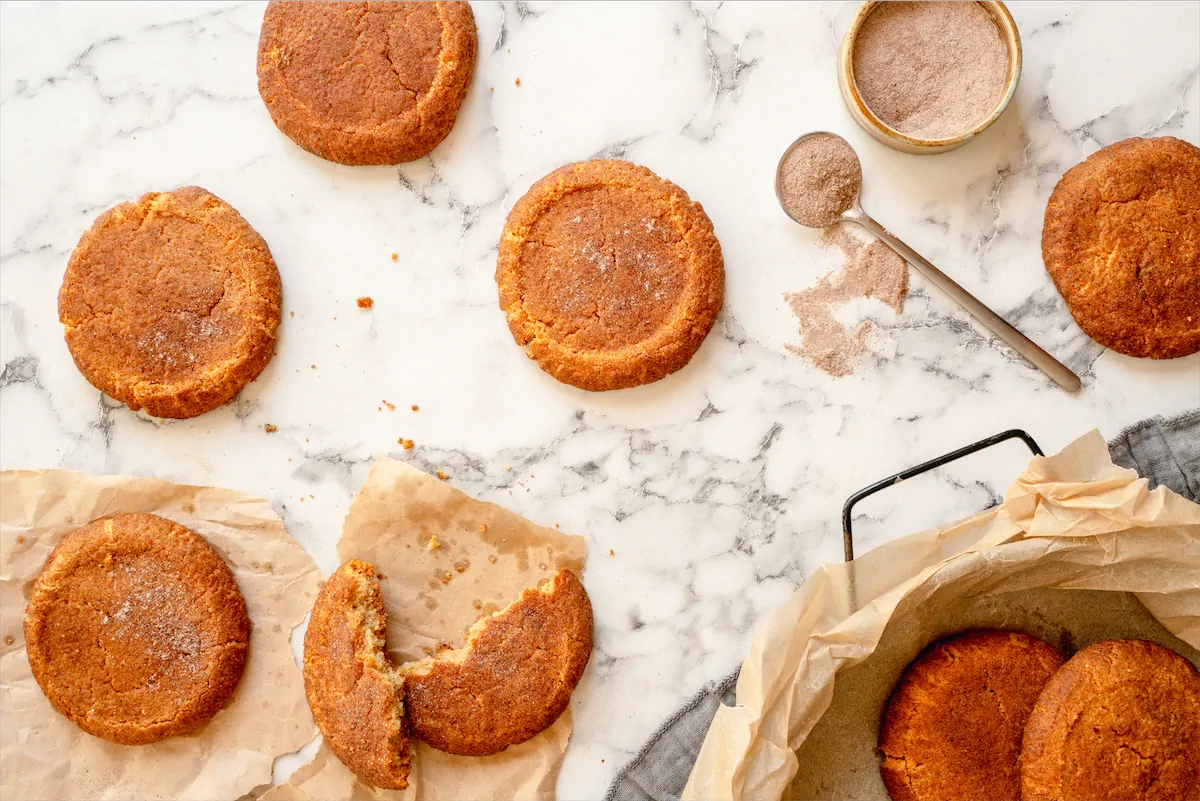 Homemade snickerdoodles are displayed on the table and one is broken revealing the texture.