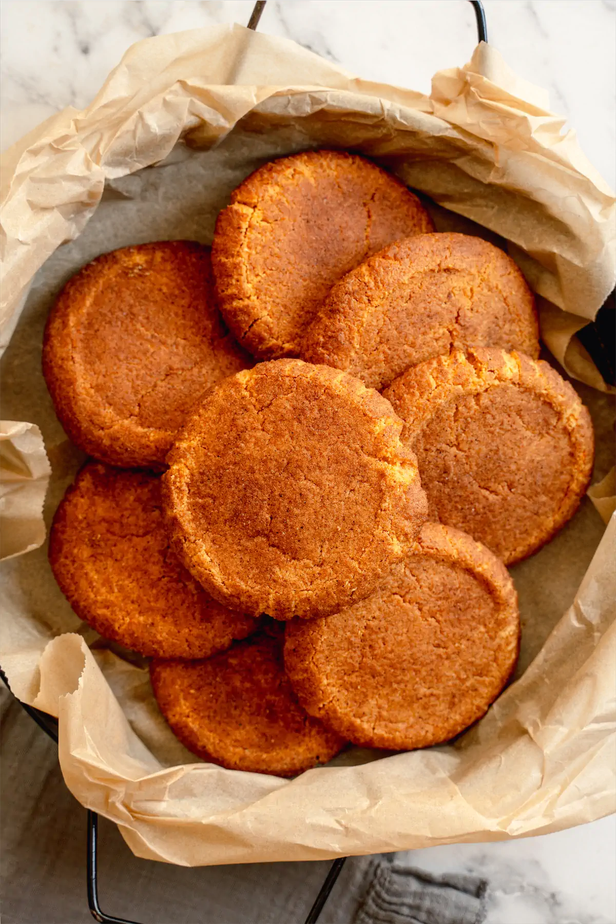 Freshly baked sugar-free snickerdoodles arranged on a deep skillet lined with parchment paper.