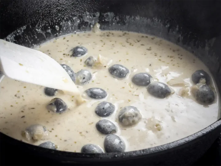 Stirring the creamy base of the homemade Tuscan chicken with a white silicone spatula.