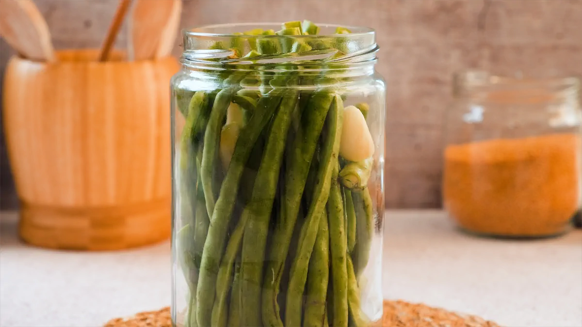 Green beans and garlic cloves in a glass jar.