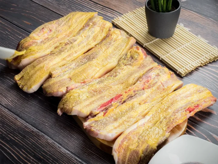 Pork ribs brushed with thin layer of yellow mustard on a plate.