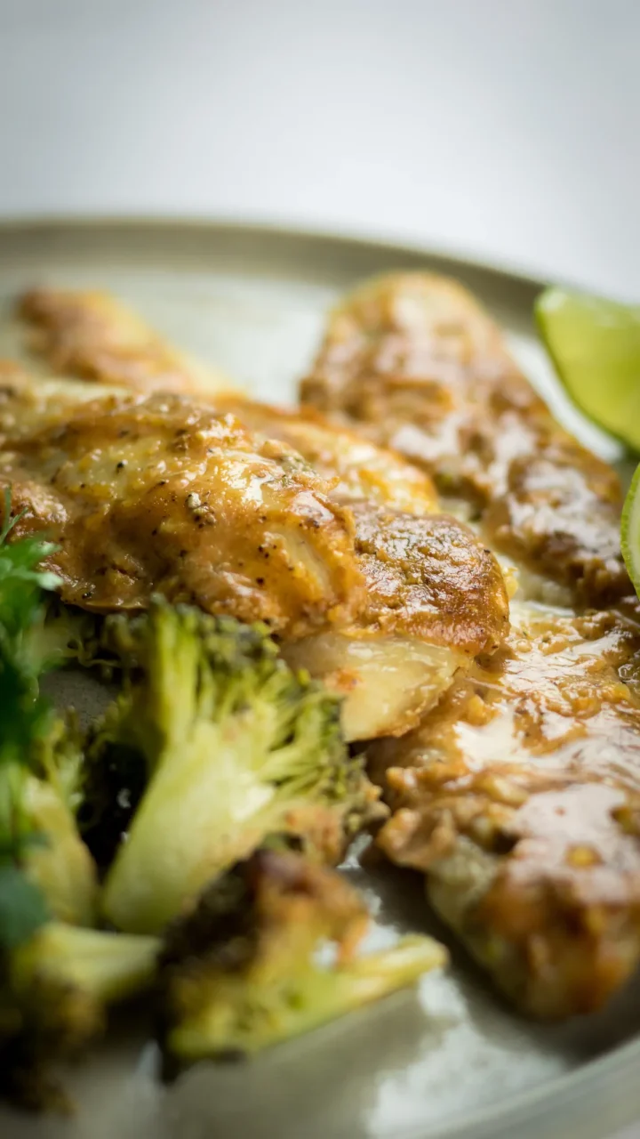 Baked cod and broccoli with tahini sauce served on a plate.