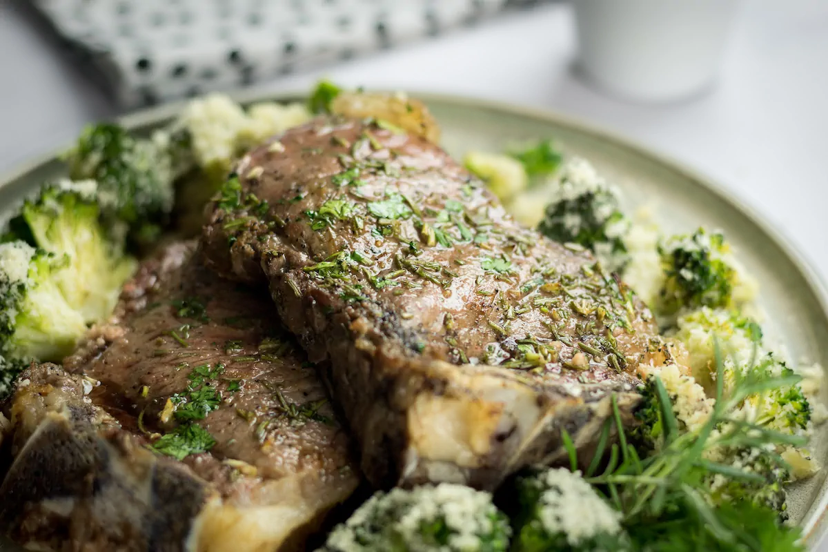 Oven-baked ribeye steak paired with cheesy roasted broccoli on a plate.