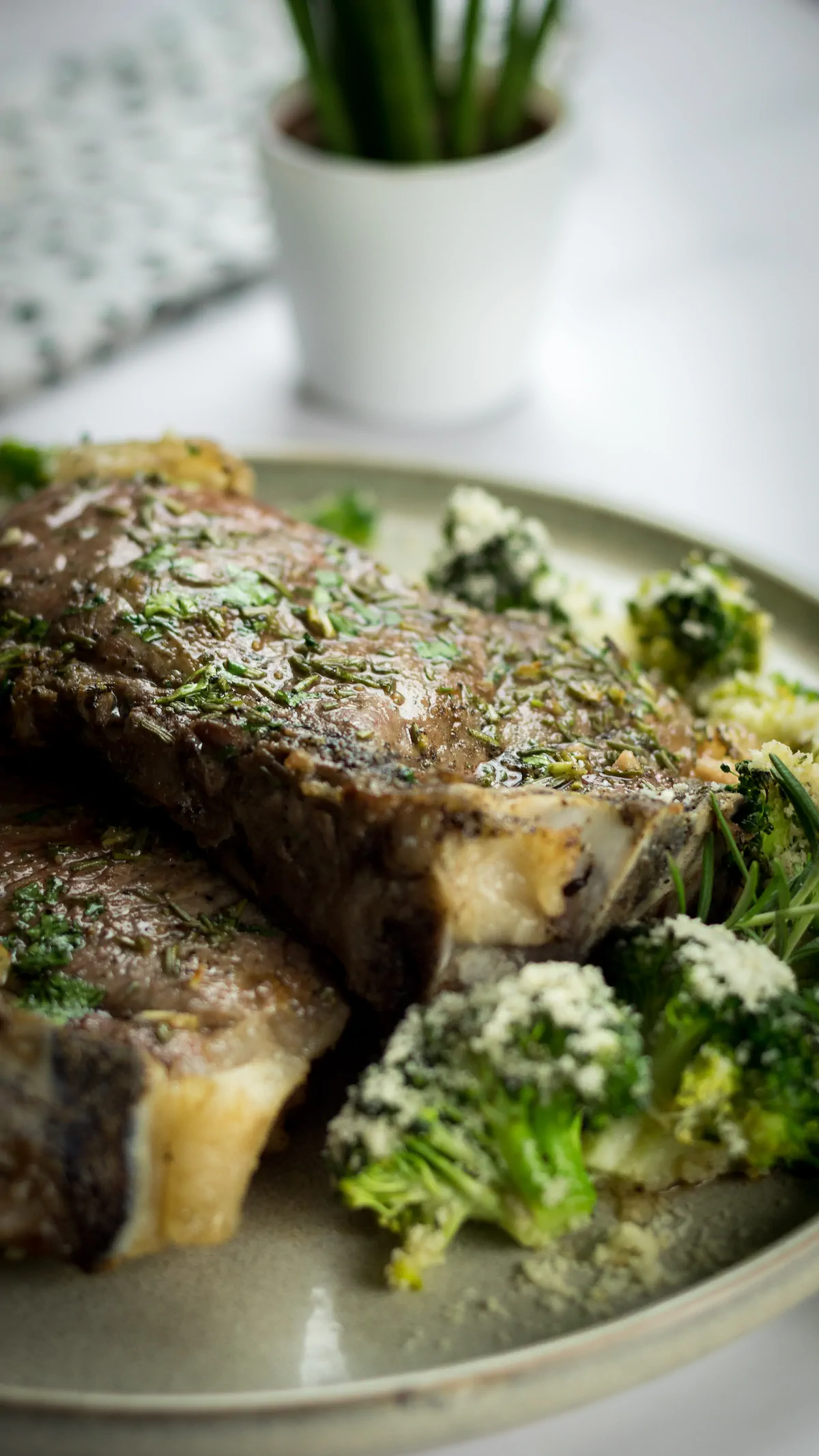 Plate of homemade baked ribeye steak and cheesy roasted broccoli.