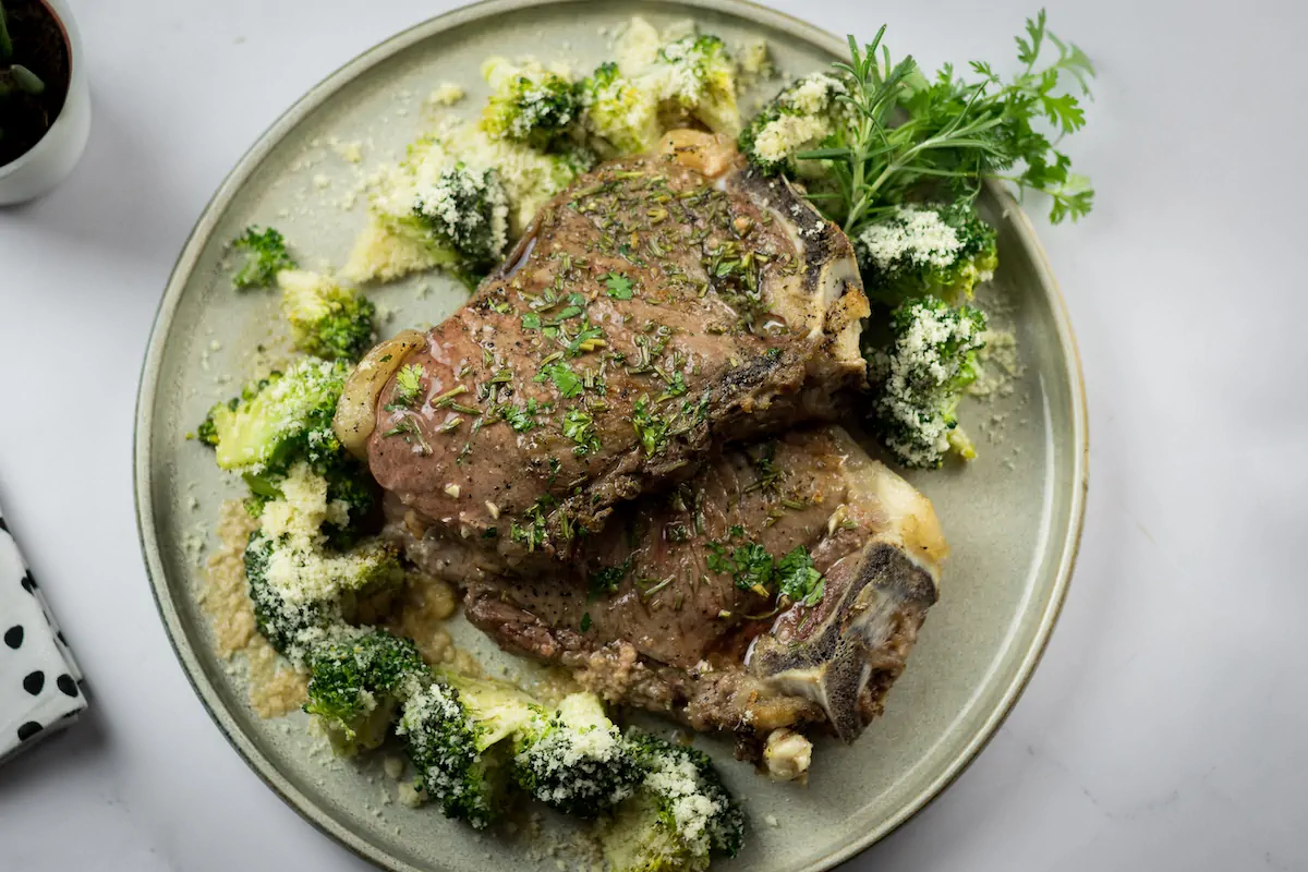 Homemade ribeye steak, baked and served with cheesy roasted broccoli and garnished with fresh herbs.