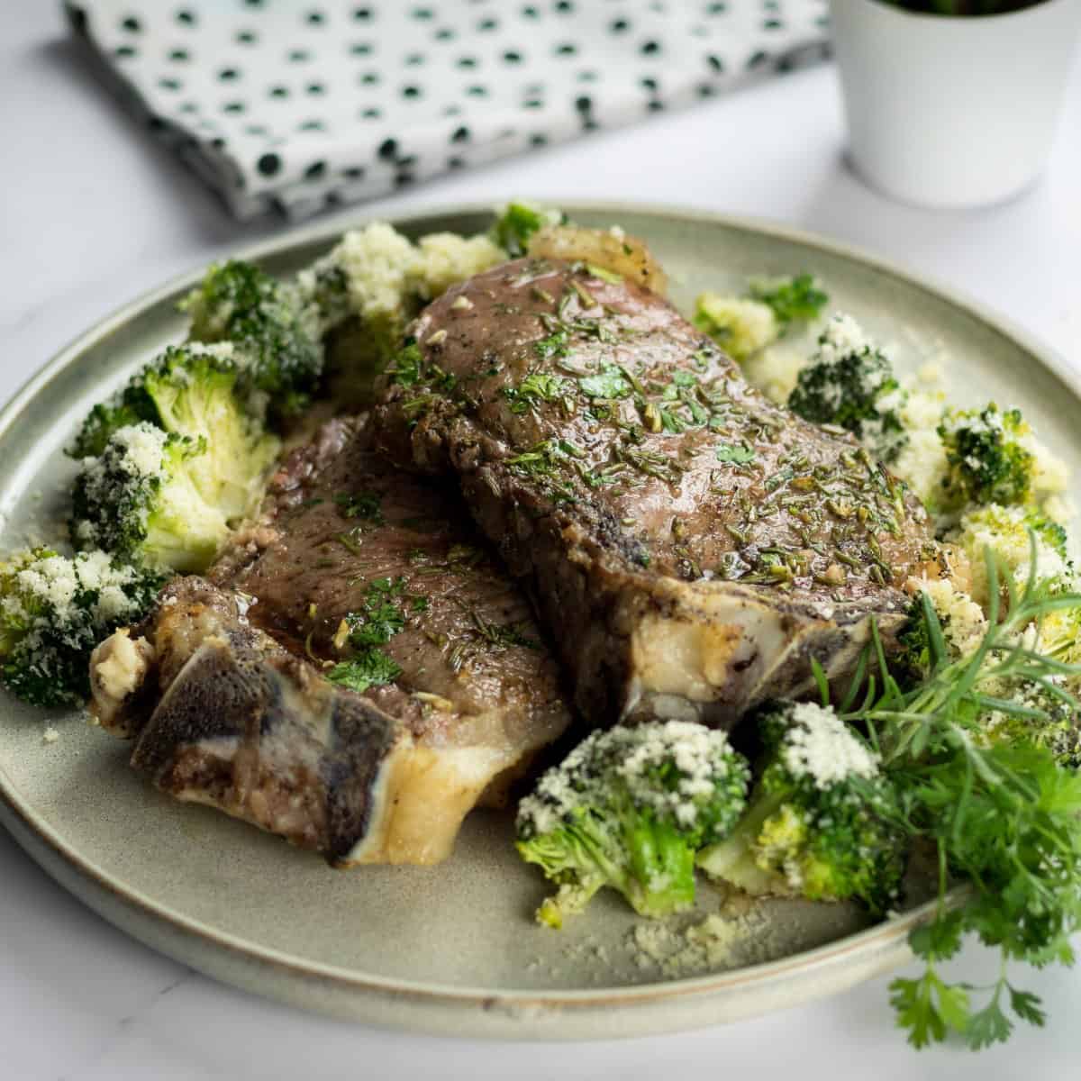 Oven baked ribeye steak recipe with cheesy roasted broccoli served on a plate.