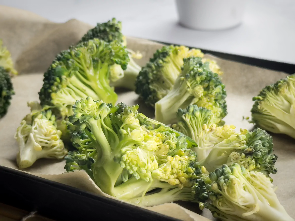 Broccoli florets on a baking tray lined with parchment paper.