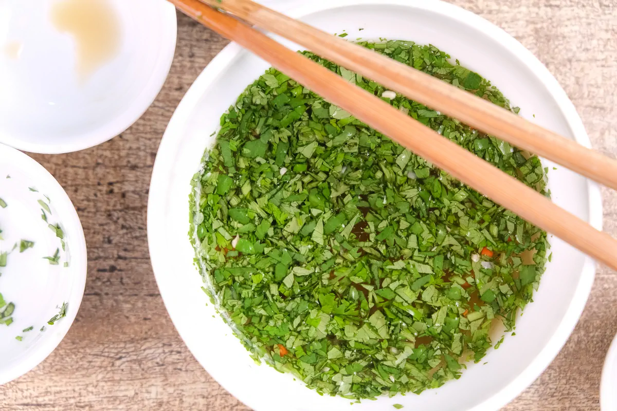 A bowl of dipping sauce with fish sauce and chopped cilantro