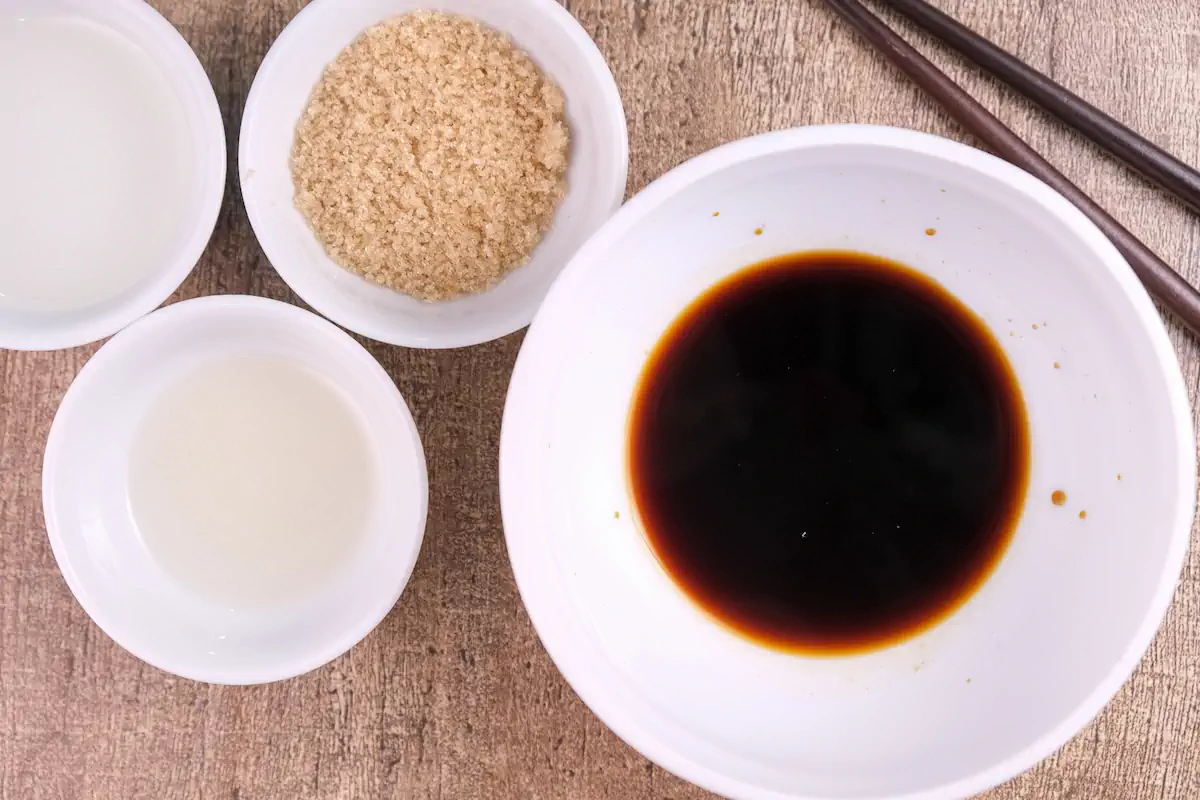 The required amount of Dashi stock granules, Japanese soy sauce, and sake in separate bowls.