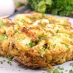 Easy oven roasted cauliflower steak served on a plate garnished with fresh green herbs.