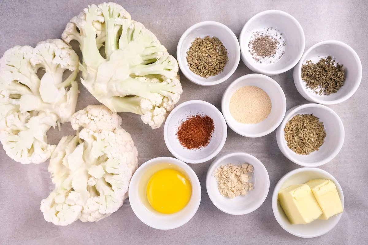 All the ingredients required to make cauliflower steak gathered and displayed on the table.
