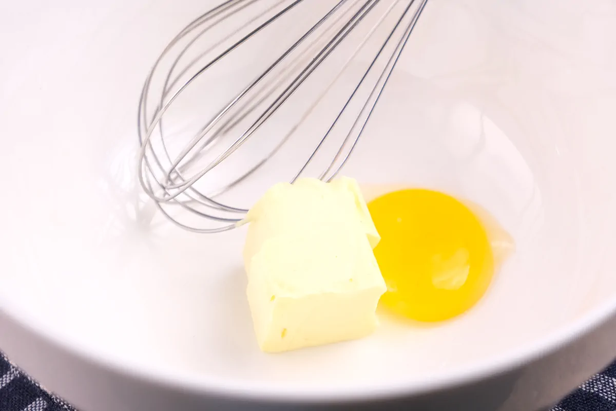 An unsalted butter and egg yolk in a large bowl with a whisk.