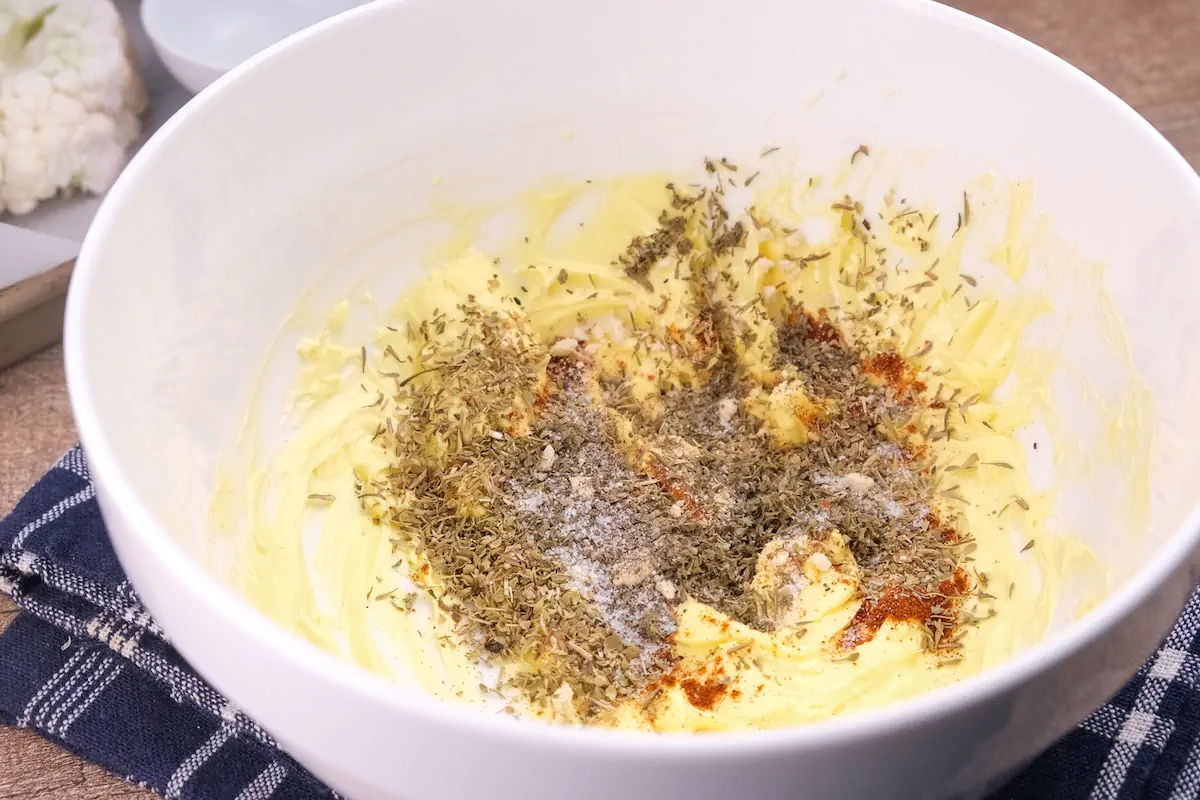 Spices added to a bowl with a mixture of butter and egg yolk .