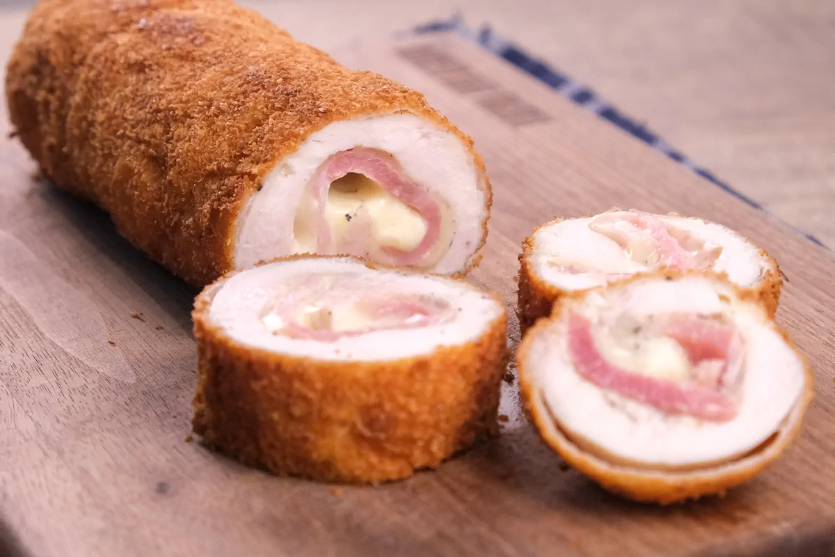 Homemade chicken cordon bleu getting sliced showing the layers inside.