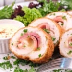 Low-carb chicken cordon bleu sliced and served alongside a bowl of creamy sauce.