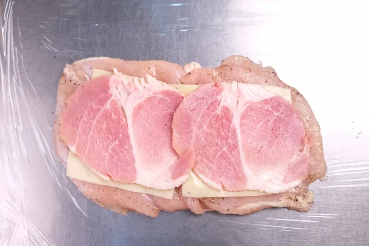 Ham and cheese layered on top of the flattened chicken breast.