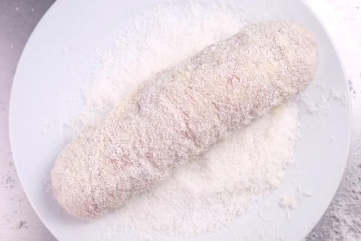 Rolling the roulade in a plate of desiccated coconut.