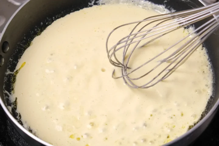 Whisking the creamy sauce in a pan.