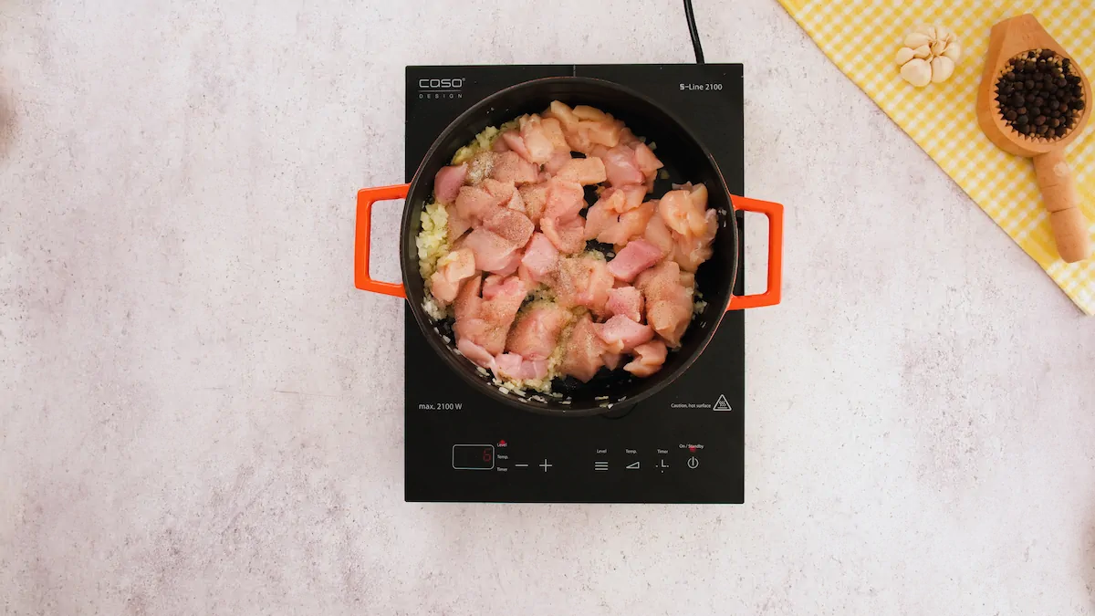 Cooking chopped chicken with sauteed onion in a cast iron skillet.