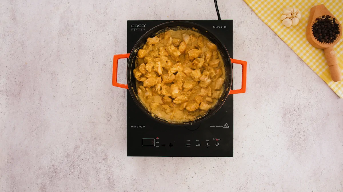 Cooking the chicken with yogurt mixture in an induction cooktop.