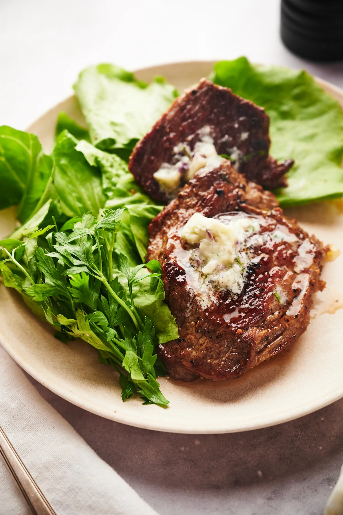 Low-carb flat iron steak with a generous dollop of herb butter and a side of greens.