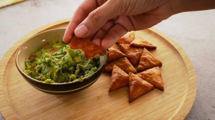 Scooping guacamole in a bowl with a keto tortilla chip.