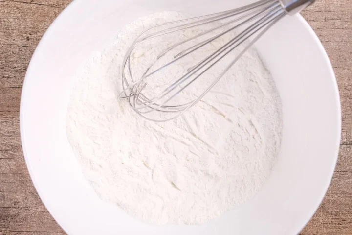 Mixing coconut flour, protein powder, baking powder, and salt in a big bowl with whisk.